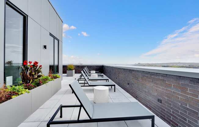 a rooftop terrace with tables and chairs and a brick wall