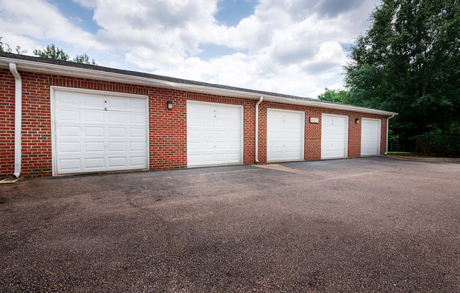 A red brick building with four white garage doors.