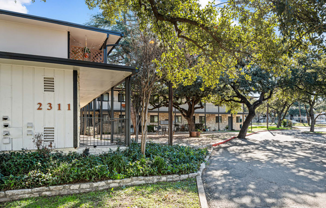 a building with a yard and trees in front of it