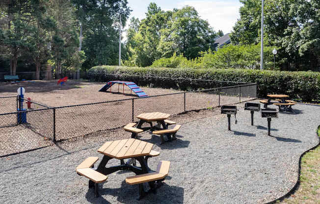 a playground with picnic tables and a chain link fence