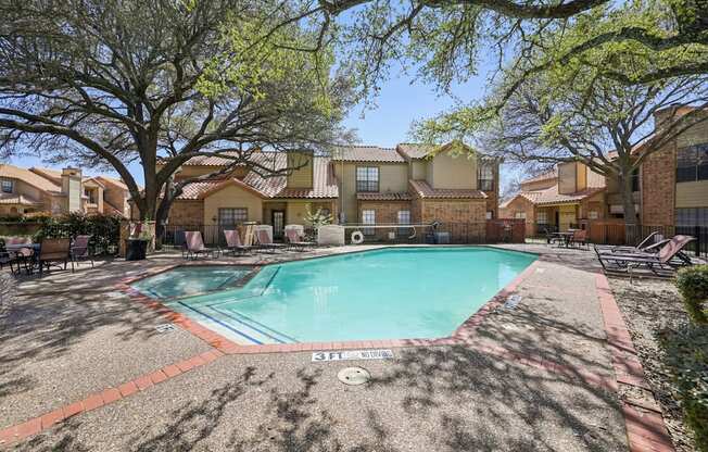 A pool surrounded by trees and houses.