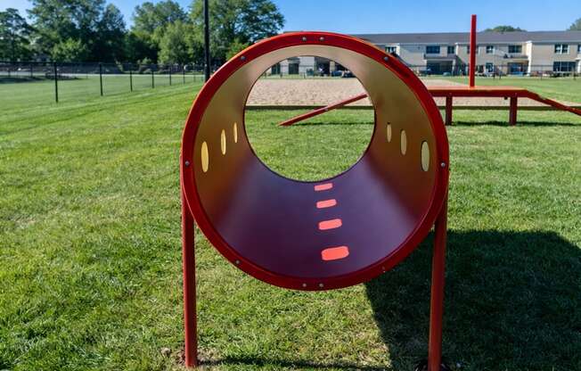 A red and purple playground slide in a grassy field.