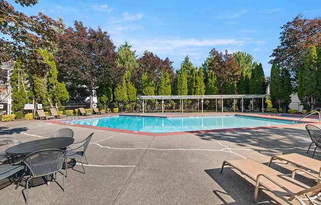 A pool surrounded by trees and chairs at Clackamas Trails Apartments, Oregon, 97222