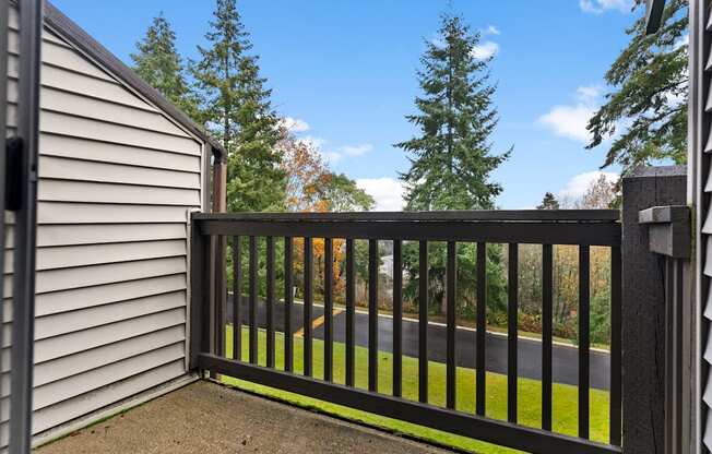 A black metal fence with a gate is in front of a house and trees.