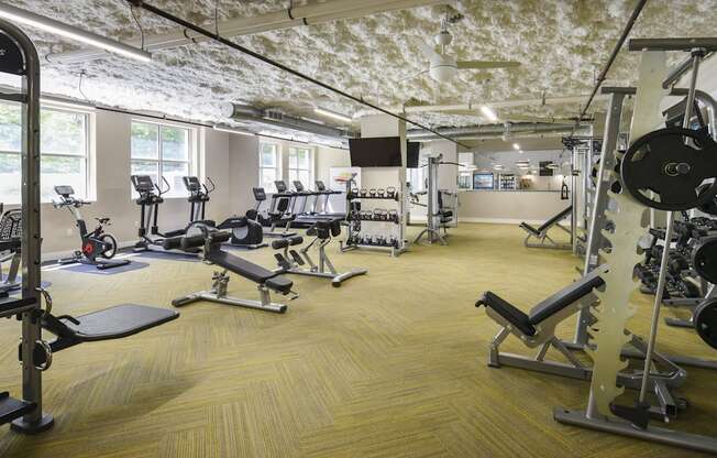 a gym with weights and cardio equipment in a building with exposed ceilings
