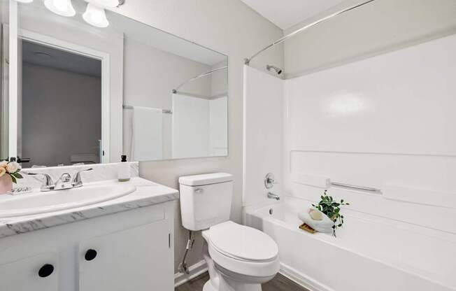 A white bathroom with a toilet, sink, and bathtub.