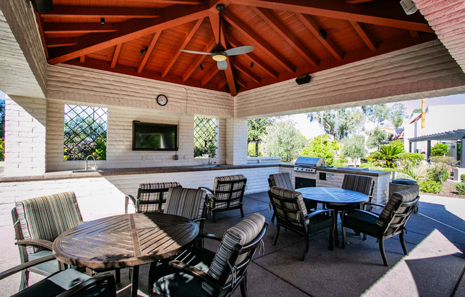 a covered patio with tables and chairs and a grill