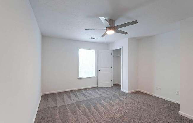 Carpeted bedroom with ceiling fan and closet