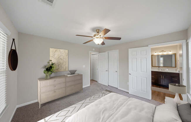 A bedroom with a white bed and a ceiling fan.