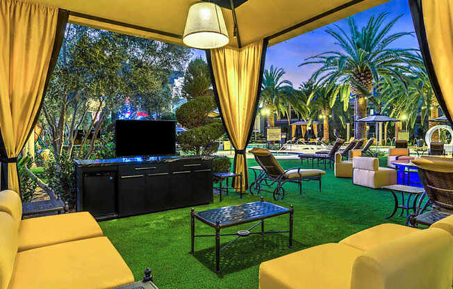 A cozy outdoor seating area with a television and comfortable chairs.