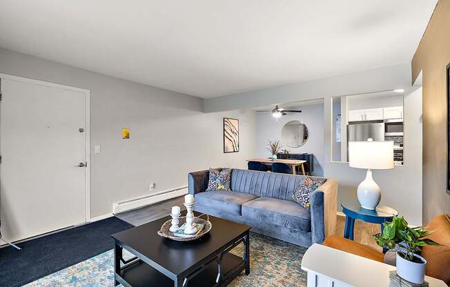 A living room with a grey couch, a black coffee table, and a blue side table.