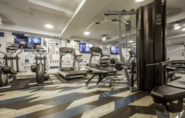 a gym with exercise machines and a wall covered motivational words wall-paper