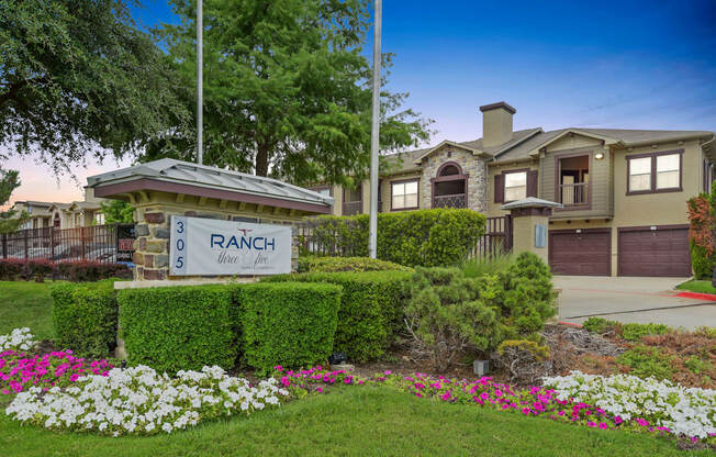 a home with a ranch sign in front of a yard with flowers
