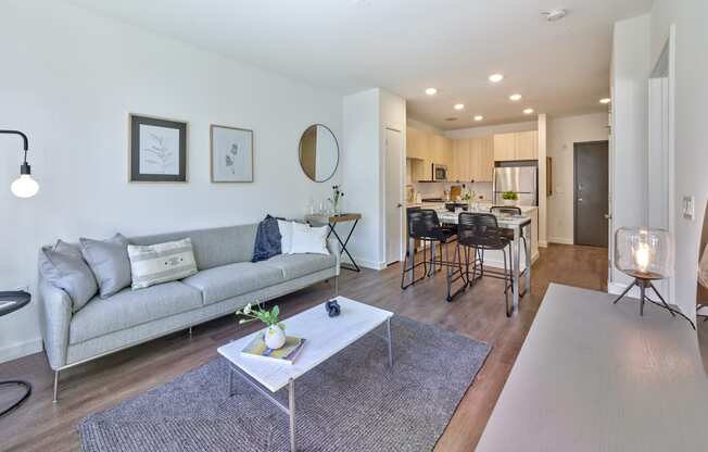 Contemporary living room at The Mint Rahway with a stylish gray sofa, a marble coffee table, and a large window, offering a comfortable space for luxury apartment rentals near the Rahway Train Station.