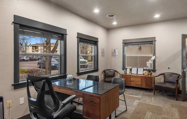 A room with a desk and chairs and a window.