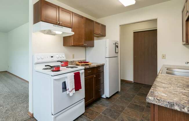 a kitchen with white appliances and wooden cabinets and a white refrigerator. Fargo, ND Islander Apartments