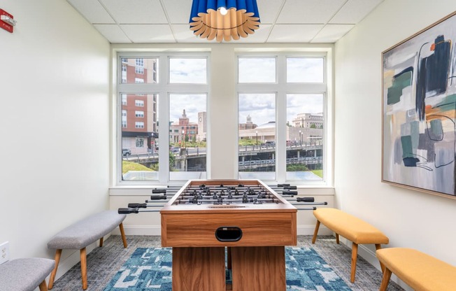 a room with a foosball table and a view of the city