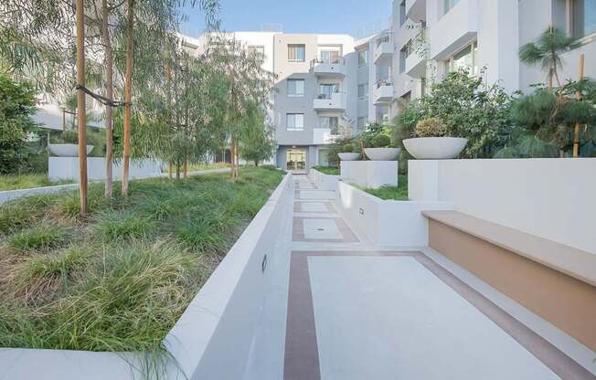 A modern building with a white exterior and a long white pathway leading to the entrance at Woodley Sara Apartment, Van Nuys, California