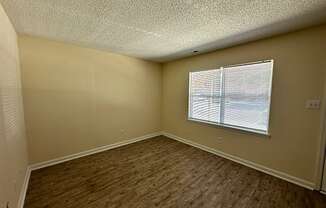 an empty living room with wood flooring and a window