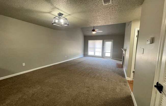 A room with a carpeted floor and a ceiling fan.