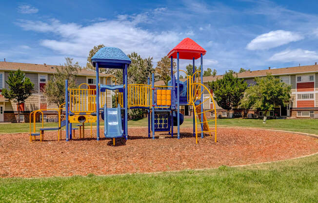 A playground with a blue and yellow slide and a red roof.