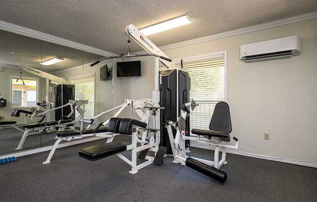 A home gym with a weight bench, barbell, and dumbbells.