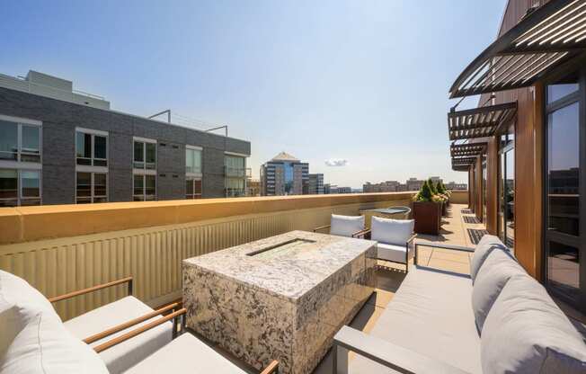 a rooftop patio with couches and chairs and a building in the background