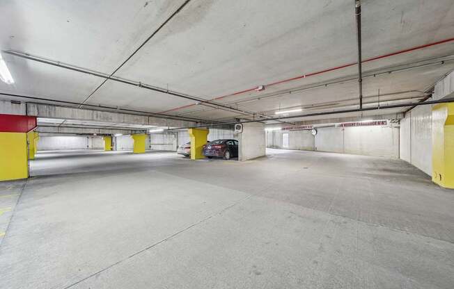 A spacious parking garage with concrete floors and yellow safety barriers.