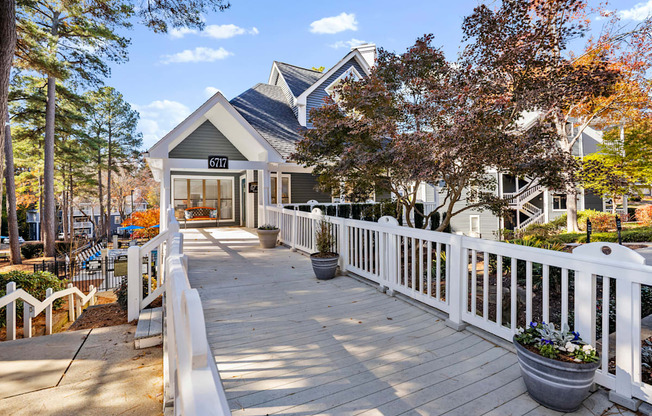 A wooden deck with a white railing and a building in the background.