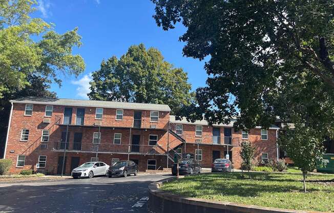 A red brick apartment building with cars parked in front.