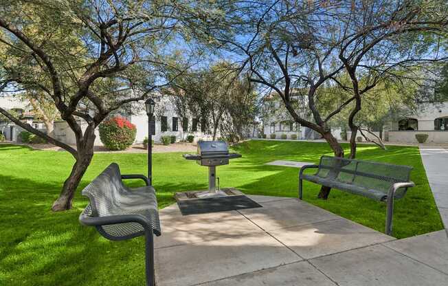 A park with a bench, a chair and a table.