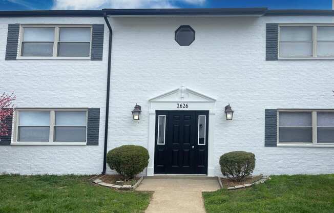 the front of a white house with a black door