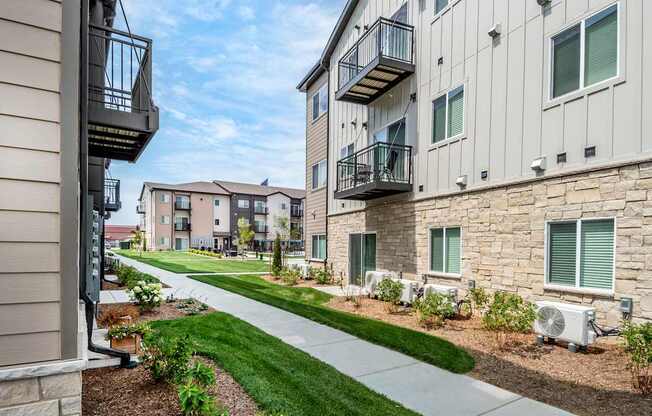 A row of apartment buildings with balconies and landscaping.