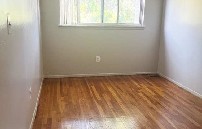 The second bedroom with a window and wooden floors.