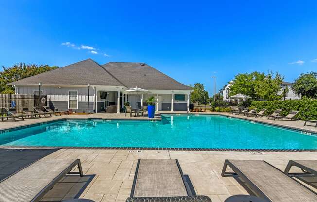 a swimming pool with chairs and a house in the background at Avalon Apartment Homes, Starkville, Mississippi