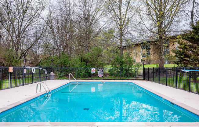 a swimming pool with a fence and trees in the background