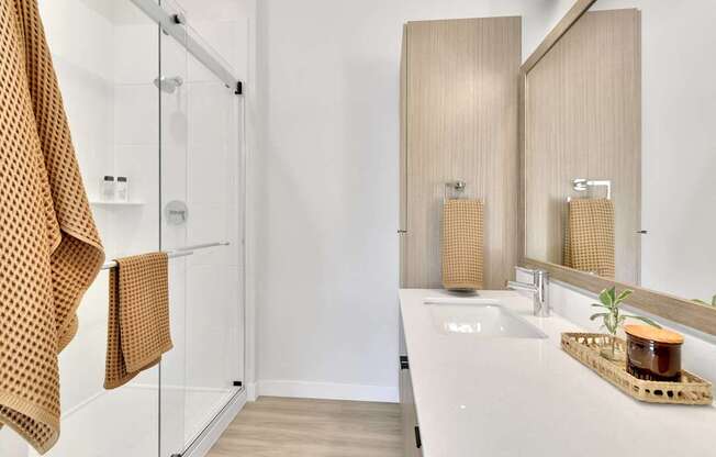 A bathroom with a white sink and a brown towel hanging on the shower rod.