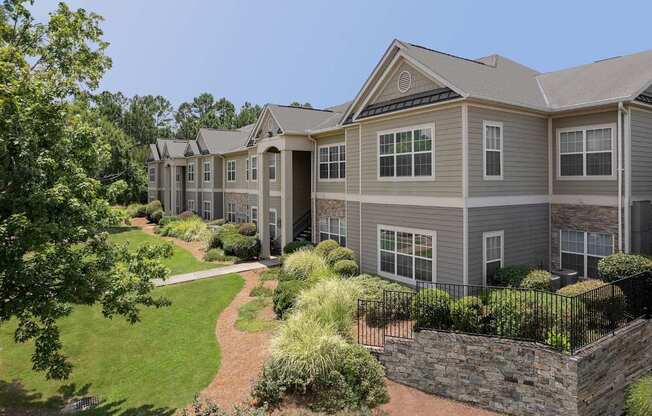 A large grey house with a stone wall in front.