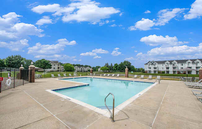 A large swimming pool surrounded by a concrete patio and lounge chairs at The Crossings Apartments, Michigan