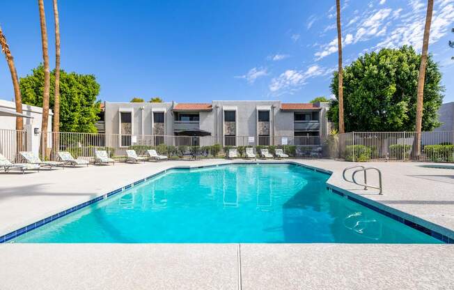 A swimming pool in front of a building with palm trees.