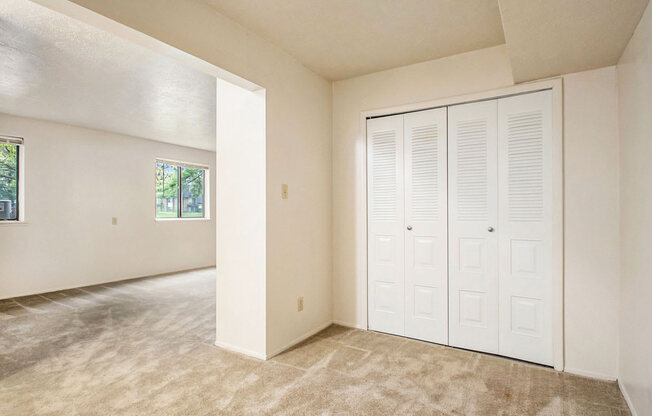 an empty bedroom with a closet and a window