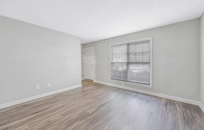 an empty living room with a large window and wood flooring