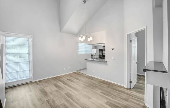 the living room and kitchen of an empty home with white walls and wood flooring