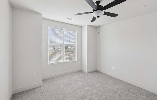 A room with a ceiling fan and carpeted floor.