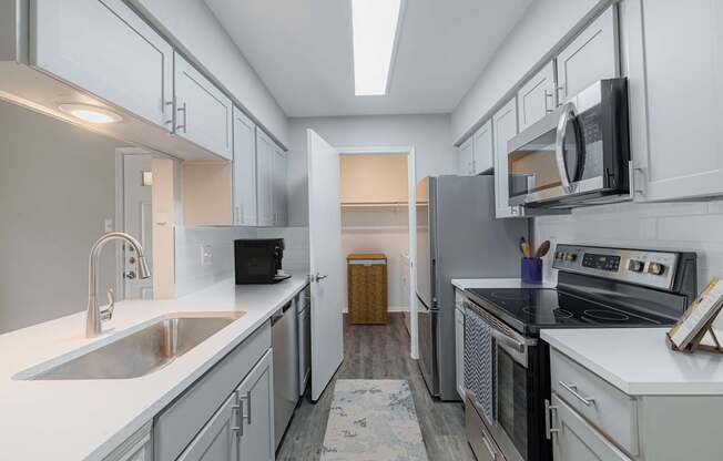 A kitchen with white cabinets and a black fridge.