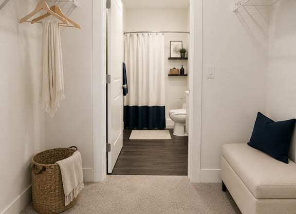 A hallway with a white couch and a toilet in the background.