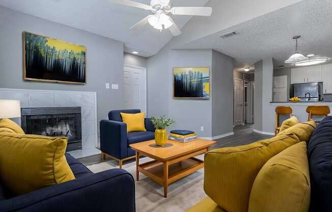 A living room with a fireplace, two couches, a coffee table, and two paintings on the wall.