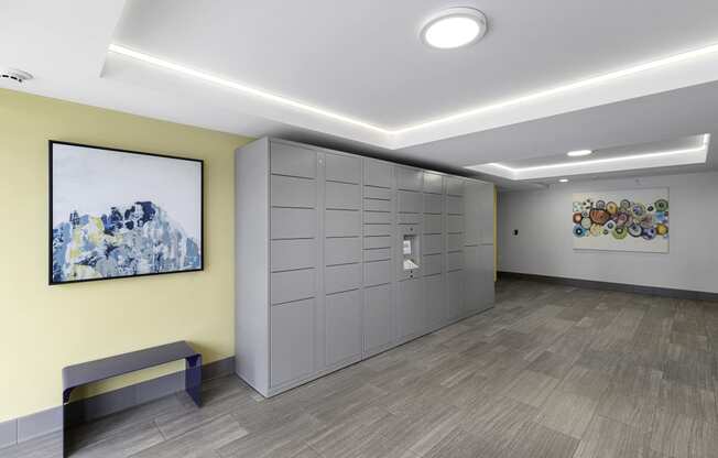 a row of package lockers with a painting on the yellow accent wall at Arabella Apartment Homes, Shoreline, 98155