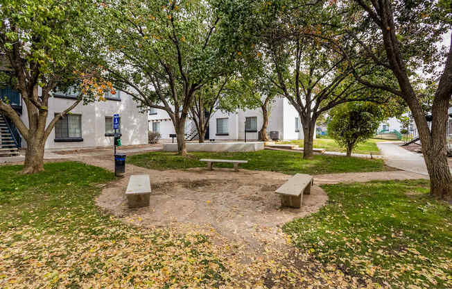 a park with benches and trees in front of a building