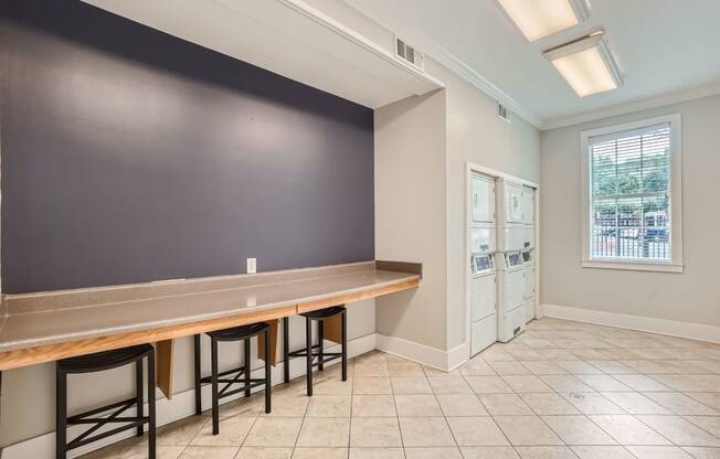 a long bar with four stools in a room with a black wall and doors